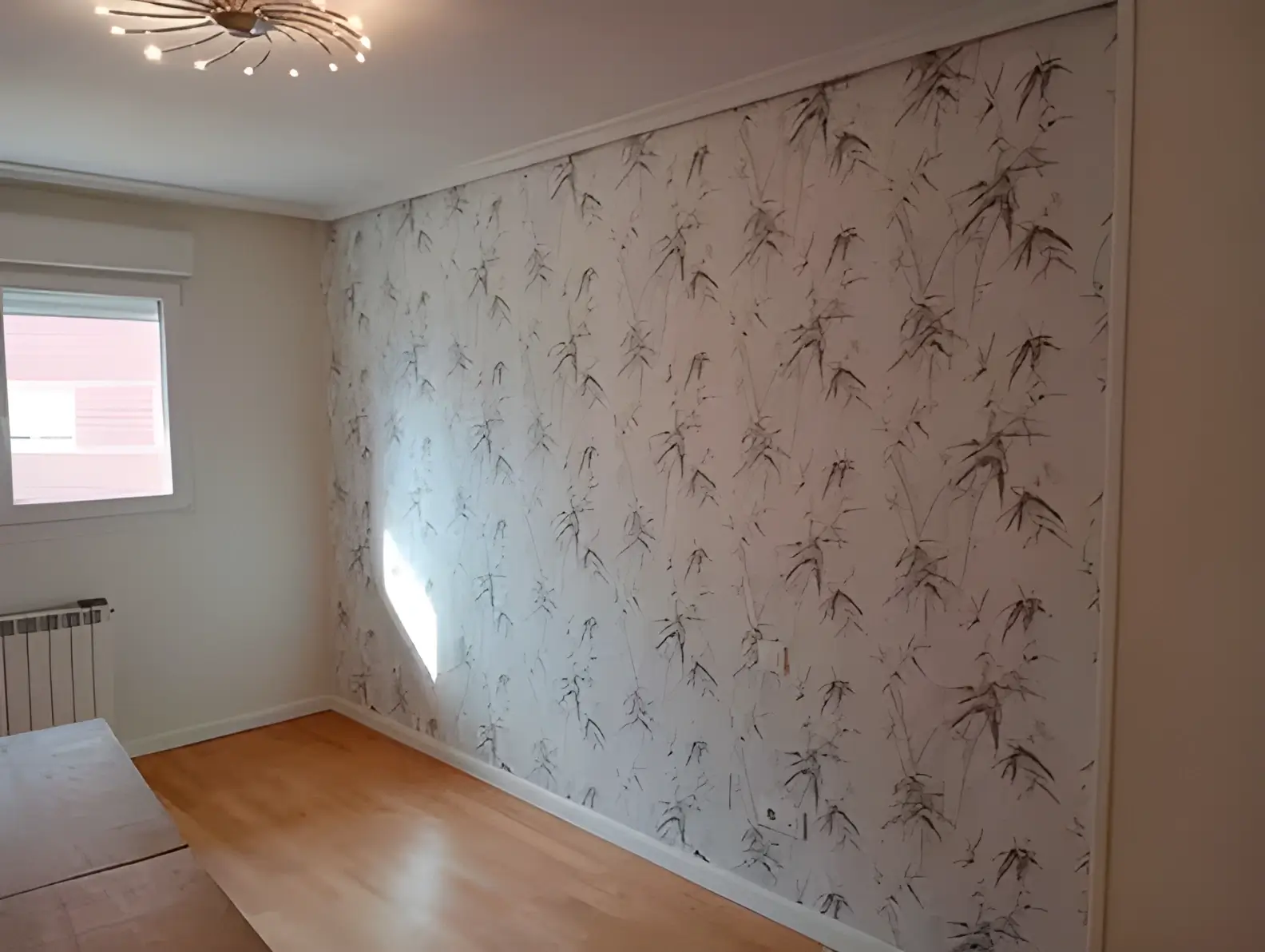 Los Pintores Alicante colocando papel pintado en pared de acento de habitación luminosa