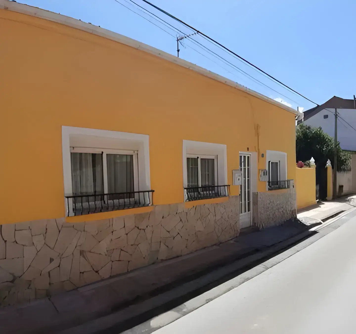 Los Pintores Alicante Fachada de casa tradicional pintada en color amarillo con zócalo de piedra